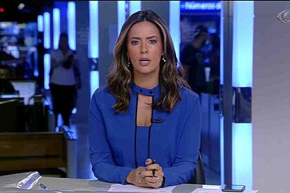 Paloma Tocci veste uma blusa azul sentada na bancada do Jornal da Band