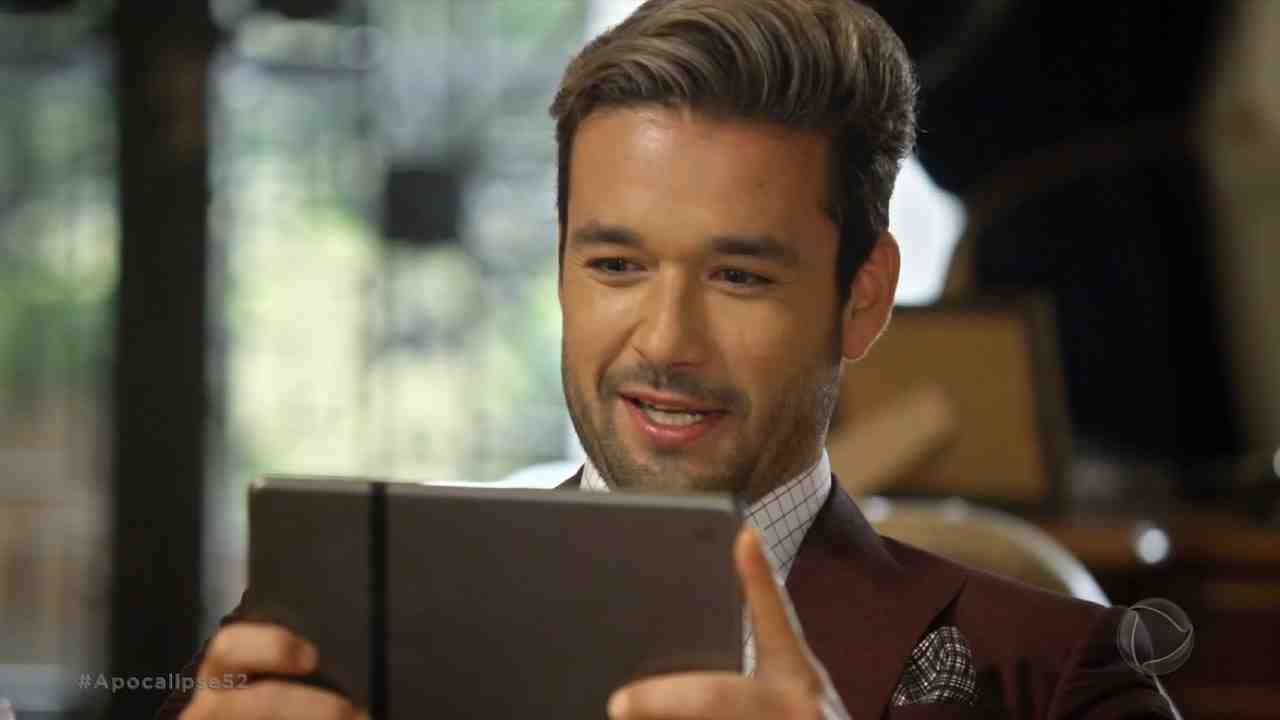 Sergio Marone em cena de Apocalipse olhando para um tablet