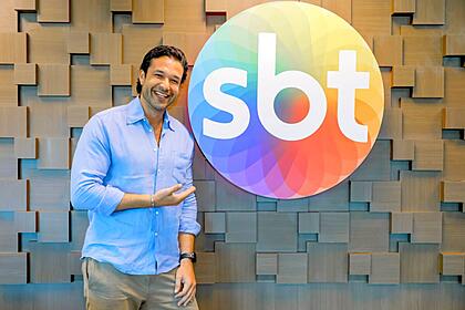 Sérgio Marone aponta para o Logo do SBT no dia da assinatura de contrato