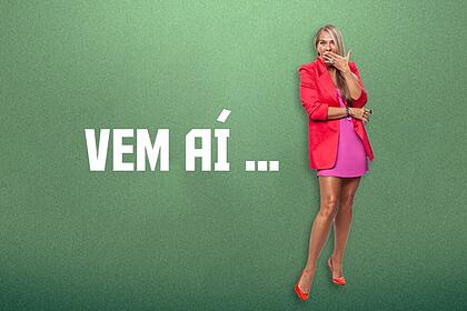Adriane Galisteu em pé ao lado do letreiro Vem aí, anunciando A Fazenda 13