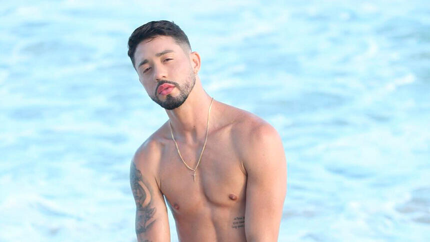 Rico Melquiades ajoelhado no mar; influencer está em A Fazenda 13
