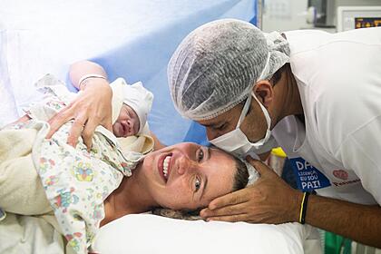 Debby Lagranha com o bebê nos braços recebe beijo do marido Leandro Amieiro