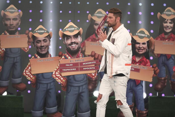 Victor Pecoraro com bonecos atrás e placas