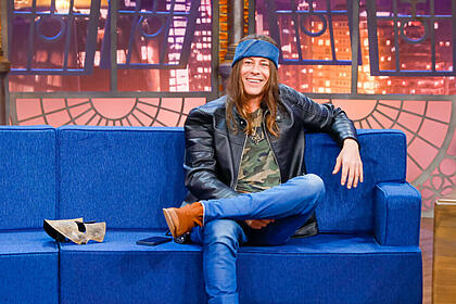 Theo Becker sentado no cenário do The Noite, durante entrevista