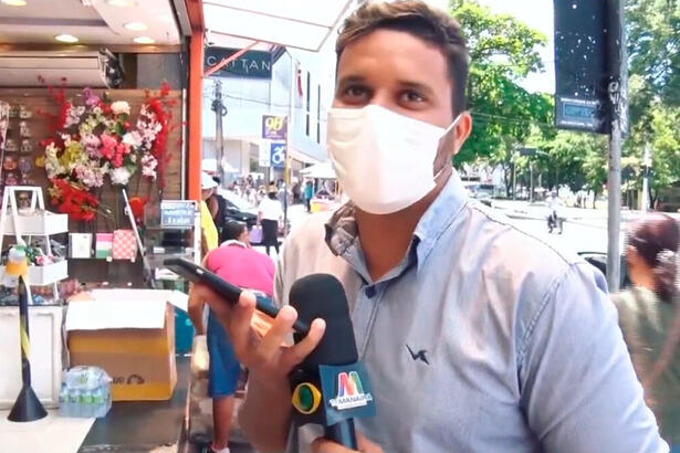 O repórter Betinho Nascimento segura o celular ao ligar para sua mãe durante reportagem para a TV Manaíra