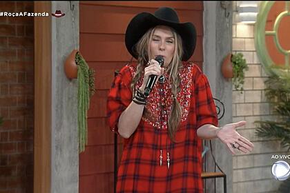 Adriane Galisteu, com um casaco vermelho, durante a apresentação do reality A Fazenda
