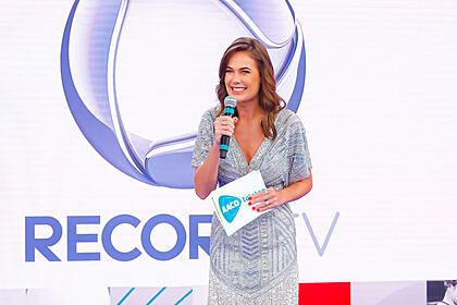 Thaís Pacholeck, atriz da novela Reis, apresentando o Teleton 2021, com o logo da Record TV no fundo