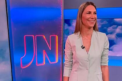 Anne Lottermann sorrir em frente ao logo do Jornal Nacional