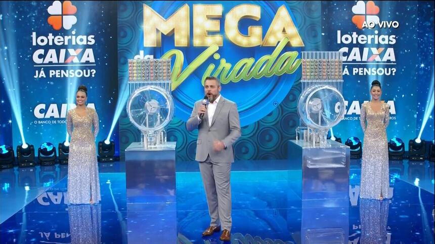 Apresentador Luigi Baricelli ao lado dos globos do sorteio da mega da virada 2021
