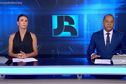 Janine borba e luiz fara monteiro sentados na bancada do jornal da record