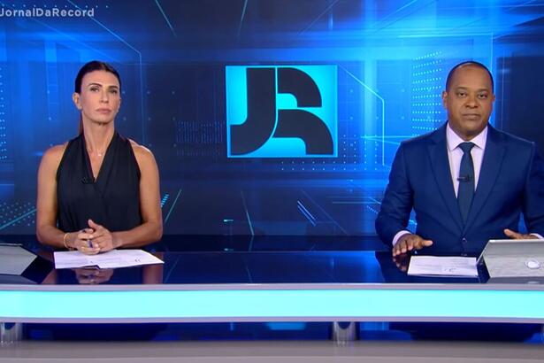 Janine Borba e Luiz Fara Monteiro sentados na bancada do Jornal da Record