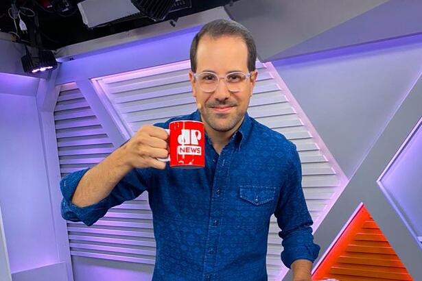 Paulo Mathias vestindo uma blusa azul e com uma caneca na mão