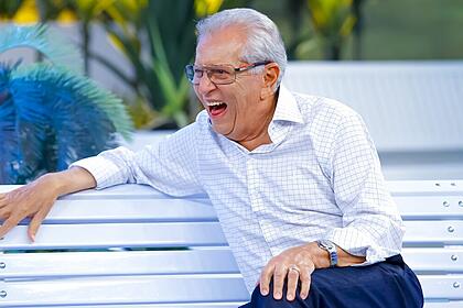 Carlos alberto de nóbrega sentando no banco da praça e rindo