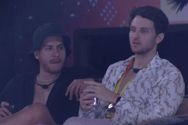 Lucas sentado ao lado de Arthur com uma latinha de bebida. Arthur de pernas cruzadas.
