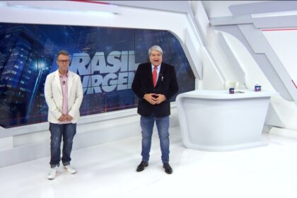 Datena de terno preto começa o programa brasil urgente sorridente, ao lado de neto