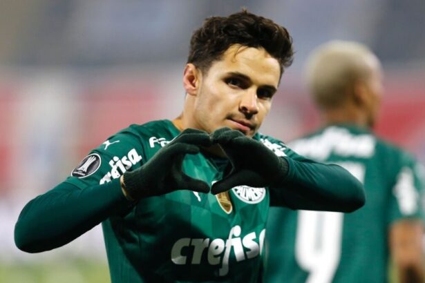 Jogador Raphael Veiga fazendo coração com as mãos e comemorando um gol com a camisa do Palmeiras