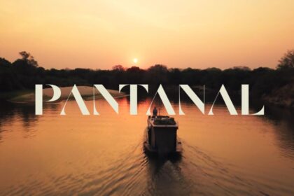Logo da novela Pantanal por traz de um rio com um barco no meio