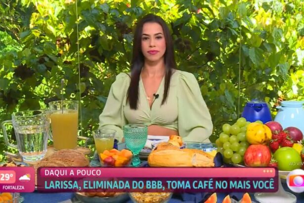 Larissa sentada de roupa verde com a mesa de café da manhã.