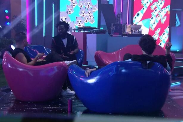 Arthur sentado em um sofá rosa ao lado de Douglas Silva