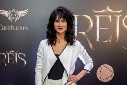 Branca messina na frente do painel com o logo da série reis da record tv