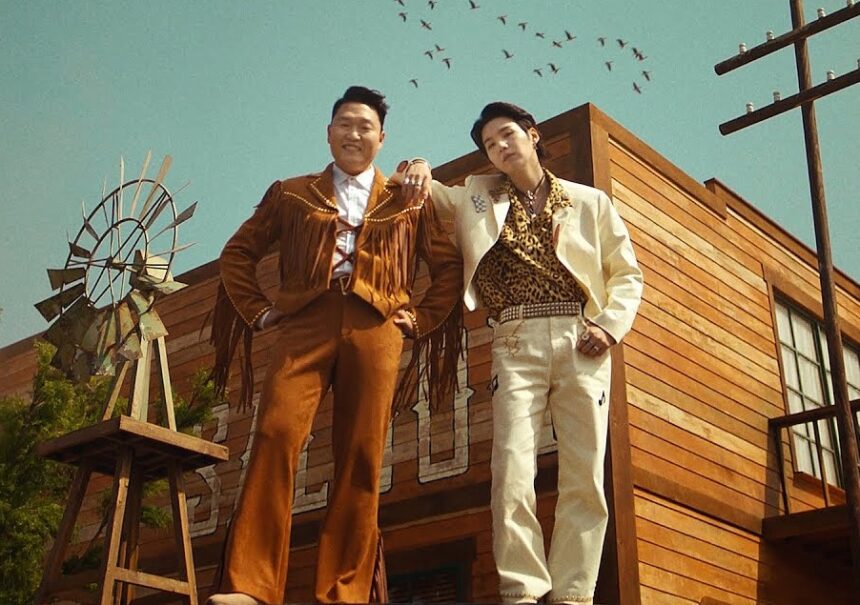 Psy e Suga abraçados em um cenário de faroeste
