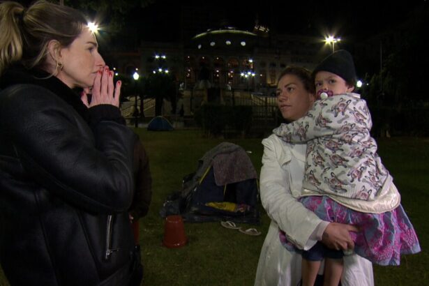 Mariana Weickert entrevistando uma mãe com uma criança de colo, em trecho de reportagem para o Domingo Espetacular