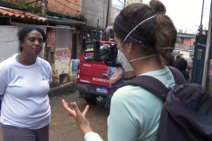 Repórter Nathalia Tavolieri entrevistando a dona Jussara, em meio ao barro da tragédia de Petrópolis