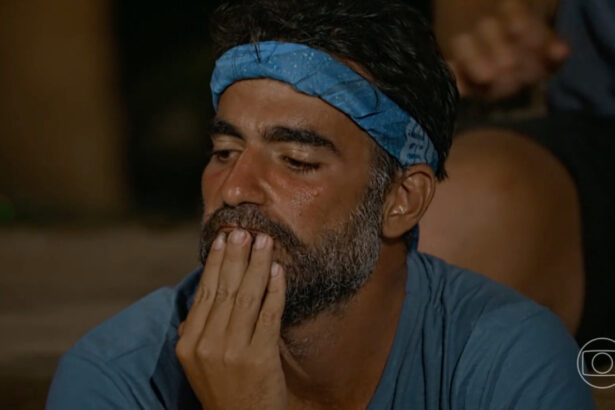 Matheus com a mão na boca e bandana azul na cabeça, reflexivo por estar no portal de eliminação