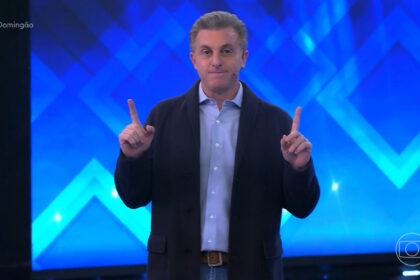 Luciano huck com os dedos apontados para cima nos estúdios do domingão