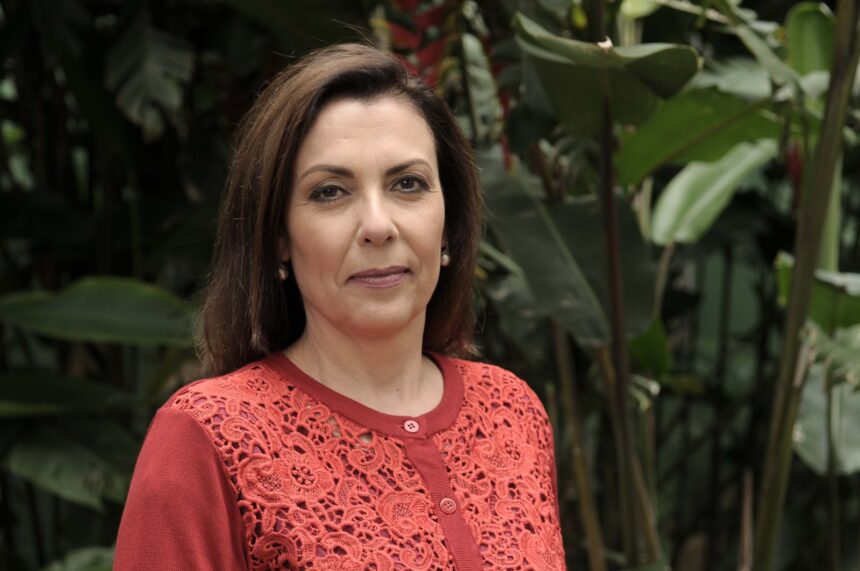 Apresentadora Márcia Bongiovanni de camisa vermelha cercada de plantas em gravação do Reporter Eco