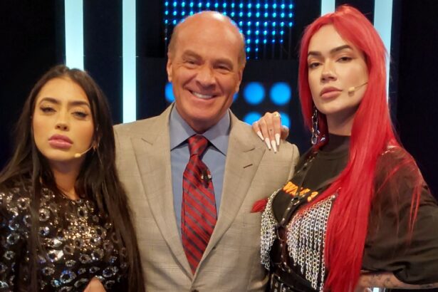 Mc Mirella de camisa e calça preta abraçada de Marcelo de Carvalho, de paitó cinza, camisa social azul e gravata magenta, sorrindo, ao lado de Laura Silva, de camisa preta durante gravação do Mega Senha, da Rede TV