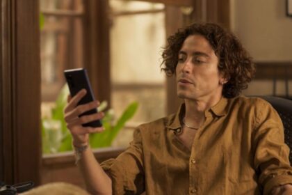 Jesuíta barbosa (jove) em cena da novela pantanal, com um celular nas mãos