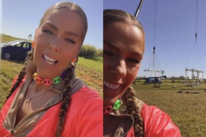 Adriane Galisteu sorridente com tranças no cabelo numa área com guindastes.