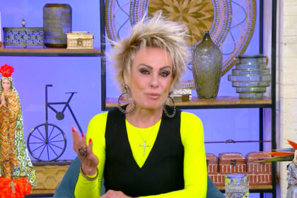 Ana Maria Braga com os olhos marejados, sentada na bancada do Mais Você