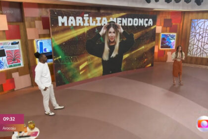 Patrícia Poeta e Manoel Soares nos estúdios do Encontro, em frente ao telão em que está projetada a imagem de Marília Mendonça