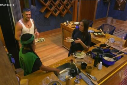 Caique na cozinha ao lado de Jaciara que se encontra de costas na imagem e Ste Viegas.