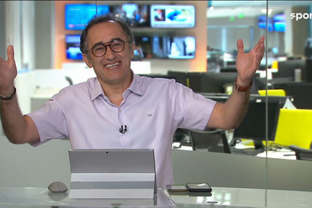 Marcelo Barreto com os braços abertos, nos estúdios do Redação SporTV, mostrando a redação de esportes da Globo ao fundo