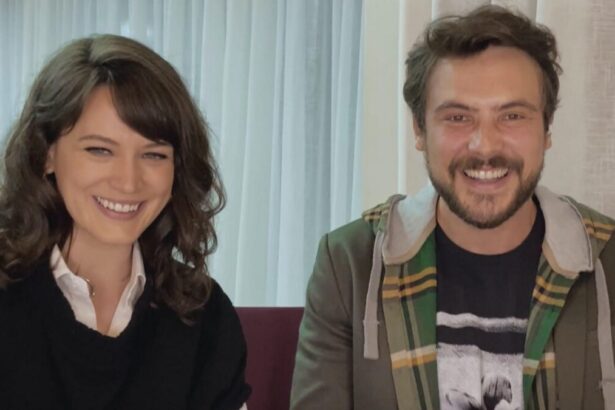 Bianca Bin sorrindo, de cabelo solto, usando camisa preta, sentada ao lado de Sérgio Guizé, com camisa em sobreposição: frio e básica preta/estampada, sorrindo, durante entrevista com Pedro Bial