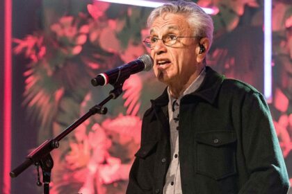 Caetano Veloso com camisa manga longa preta, sentado num banco com o microfone próximo a boca durante gravação do Conversa com Bial da TV Globo