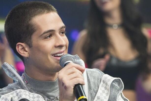 João Gomes sorrindo segurando o microfone com a mão direita durante gravação do Faustão na Band