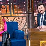 Joelma de top, ombreira e short rosa; bota cano alto preta, sorrindo, sentada num sofá azul, e cabelo solto durante gravação do The Noite com Danilo Gentili, no SBT