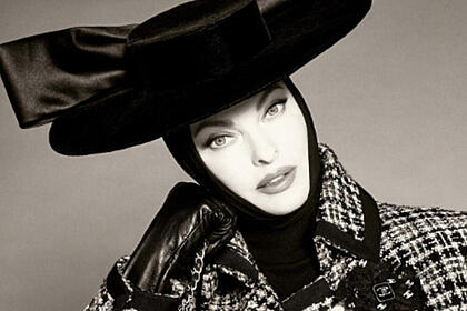 Linda Evangelista toda coberta e com chapéu preto