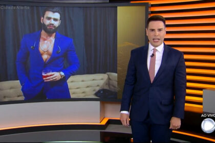 Luiz bacci no cidade alerta, em frente ao telão que mostra um imagem do gusttavo lima