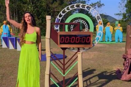 Mariana Rios de vestido verde ao lado de um cronometro no local de provas.