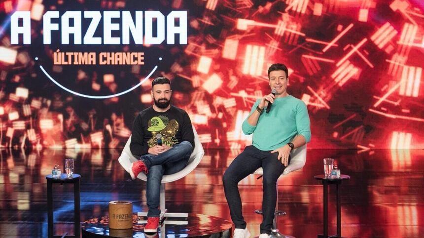 Bruno Tálamo e Rodrigo Faro nos estúdios do Hora do Faro, com a logo do quadro A Fazenda - Última Chance ao fundo