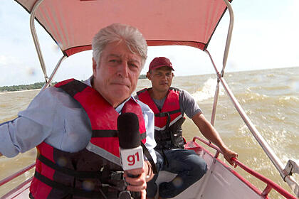 Caco Barcellos ao lado de outro rapaz, em uma lancha dentro de um rio no Pará