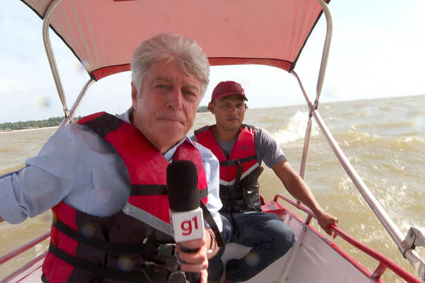 Caco Barcellos ao lado de outro rapaz, em uma lancha dentro de um rio no Pará