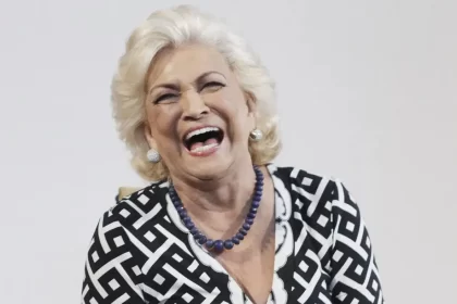 Hebe Camargo de cardigã preto e branco, com brincos e colar de brilhantes sorrindo durante ensaio fotográfico