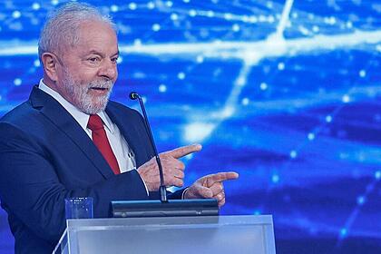 Lula de blazer azul, gravata vermelha e camisa social branca, apontando durante debate na Band