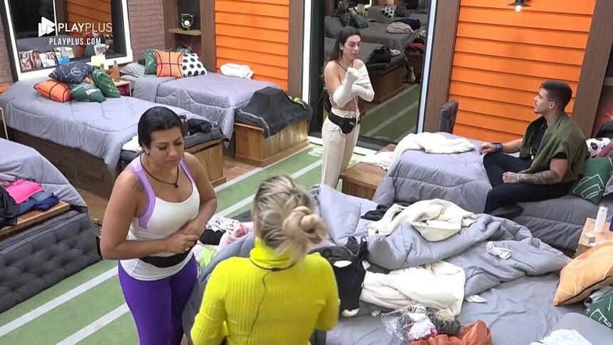 Moranguinho de roupa de ginastica de frente para Deolane que está com uma roupa amarela.